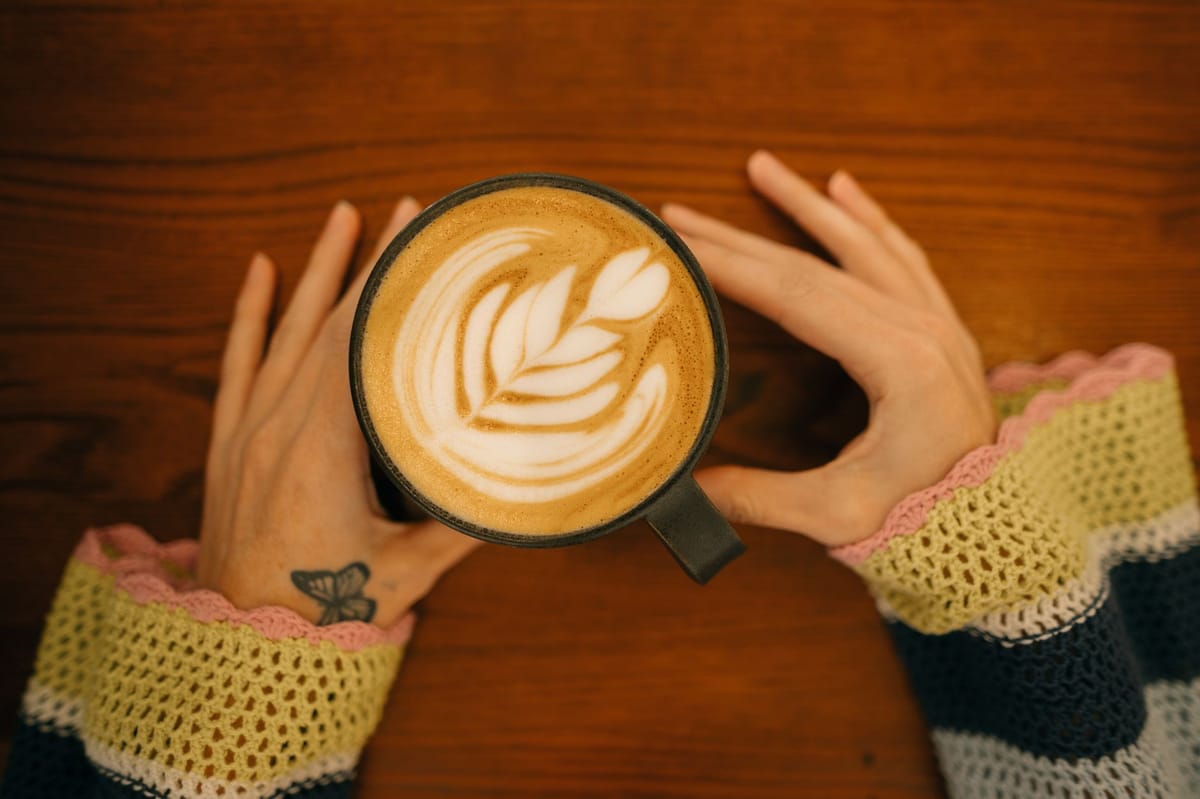 A barista holding a cup with a sleeve